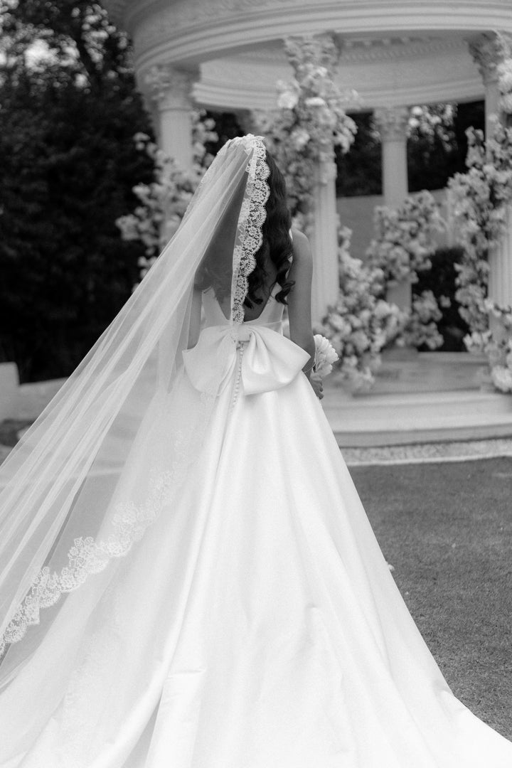 A view of the back of the dress with a large bow and extended veil