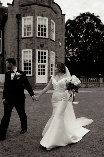 Model Walking with partner Wearing Anastasia Off The Shoulder Wedding Dress