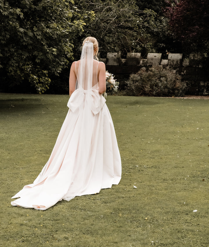 The back of the Dove Empire Blush Dress with a veil on
